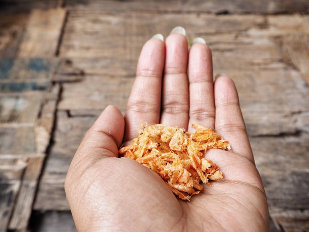 tiro cortado de pessoa segurando saboroso camarão seco na mão
 - Foto, Imagem