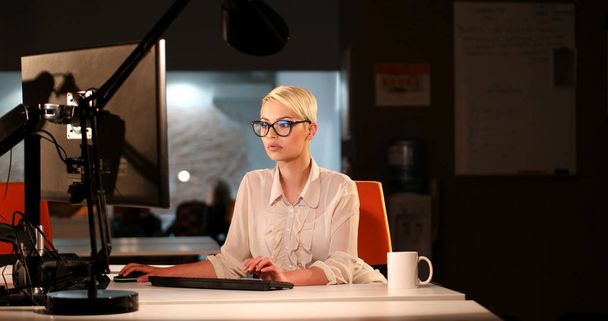 woman working on computer in dark office - Foto, imagen