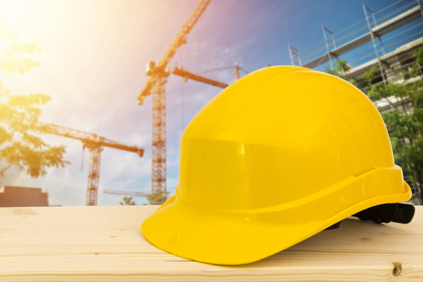 Keltainen turvakypärä ja käsineet työtasolla konstruktiossa
 - Valokuva, kuva