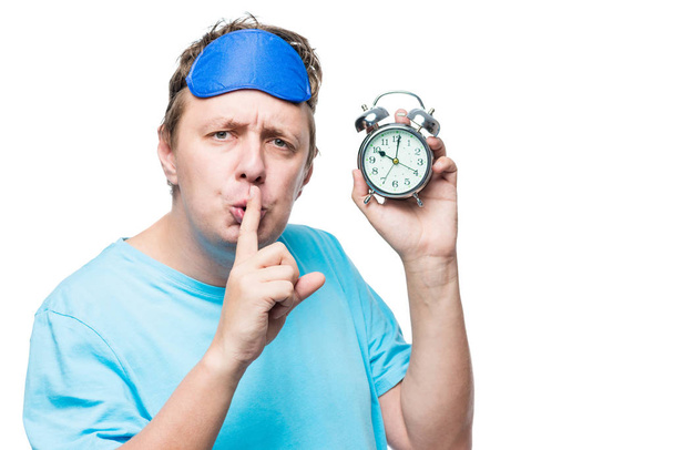 Man with an alarm clock showing a gesture quietly in a mask for  - Photo, Image