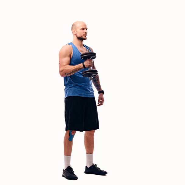 Shaved head male holds dumbbell - Photo, Image