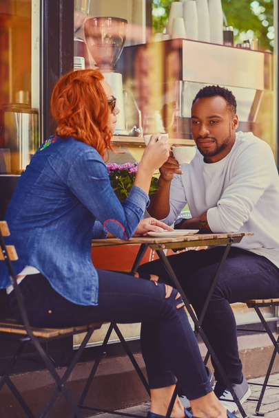 Чорний чоловік і руда жінка в кафе
 - Фото, зображення