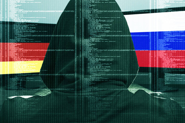 Hacker trabaja en un ataque cibernético contra Alemania y Rusia. Concepto de hackear el ordenador. Bandera de Ger y Rus en la pantalla. Bandera alemana y rusa en la pantalla
. - Foto, Imagen