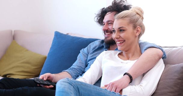 Jovem casal no sofá assistindo televisão
 - Foto, Imagem