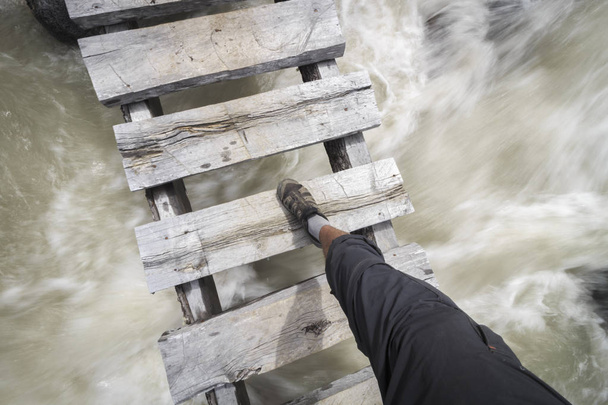 脚と足を川に架かる木製の橋を渡る - 写真・画像