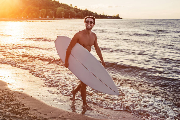 Young man with surfboard - 写真・画像