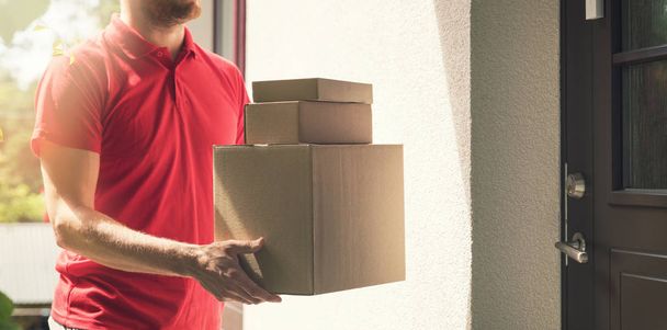 υπηρεσία παράδοσης στο σπίτι - deliveryman με κουτιά στέκεται από τις πόρτες του σπιτιού - Φωτογραφία, εικόνα
