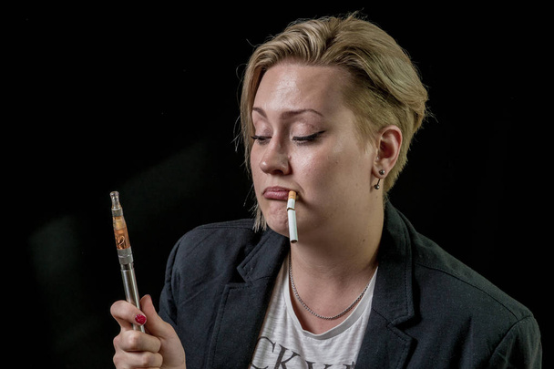 Kobieta jest przesłuchanie o vaping vaporiser trzymając tytoń papierosowy - Zdjęcie, obraz