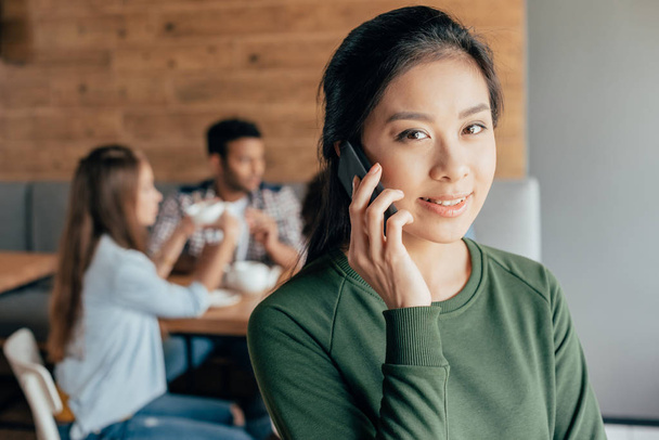 Mujer asiática hablando en teléfono inteligente en la cafetería
 - Foto, imagen