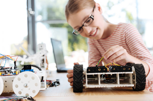 Teenage girl pulling wires of robotic car - Photo, image