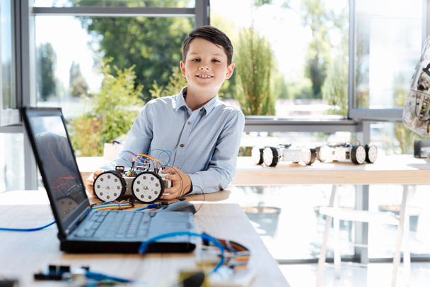 Dark-haired boy standing with his robotic car - Foto, immagini