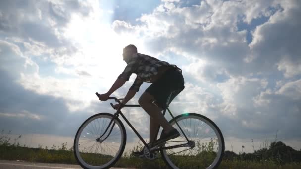 Jeune homme beau chevauchant à vélo vintage dans la route de campagne. Homme sportif faisant du vélo sur la piste. Cycliste masculin à vélo à vitesse fixe à l'autoroute. Mode de vie sain et actif Mouvement lent
 - Séquence, vidéo