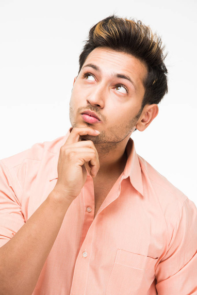 Portrait of a good looking confused Indian Man or handsome Indian man in thinking pose, standing isolated over white background - Photo, Image