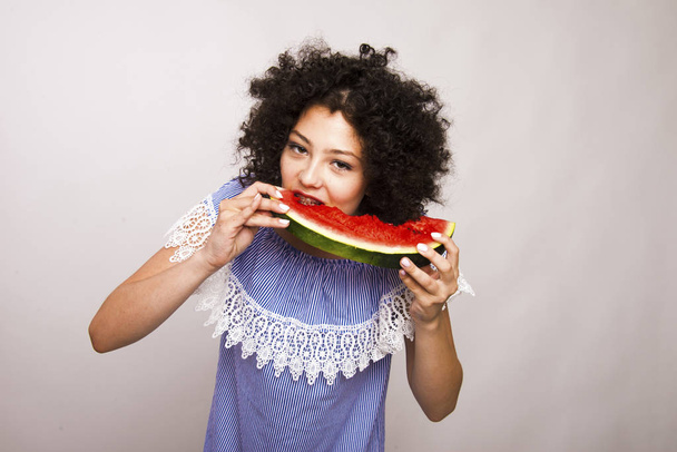 Όμορφη νεαρή κοπέλα που τρώει μια φέτα καρπούζι. - Φωτογραφία, εικόνα