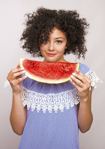 Όμορφη νεαρή κοπέλα που τρώει μια φέτα καρπούζι. - Φωτογραφία, εικόνα