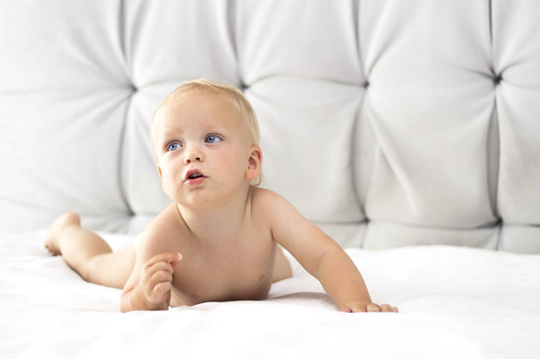 Cute toddler lying on the bed and looking away - Photo, Image