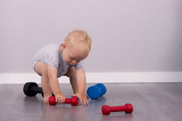 Funny baby boy playing with dumbbells. Copy space - Fotografie, Obrázek