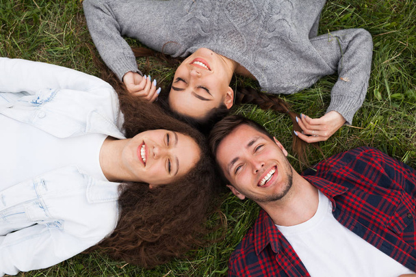 Young smiling people lying on grass - Fotó, kép
