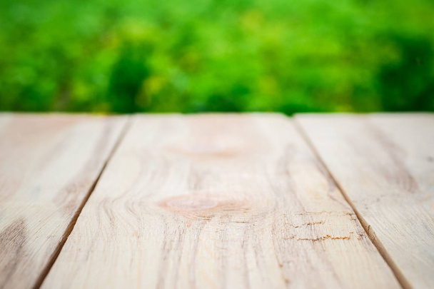 Mesa de madera sobre un fondo de árboles verdes brillantes en el desenfoque
 - Foto, imagen