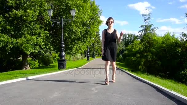 Slow Motion Happy smiling young woman in black dress walking around in sunny park on summers day. - Imágenes, Vídeo