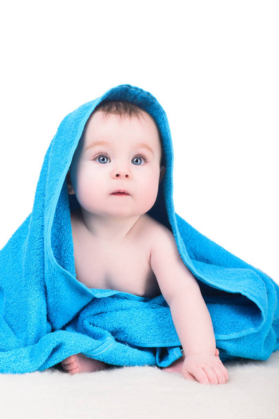 Baby with big blue eyes sitting on the blanket under towel - 写真・画像