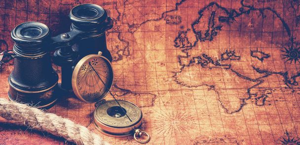 Old vintage retro compass and spyglass on ancient world map - Photo, Image