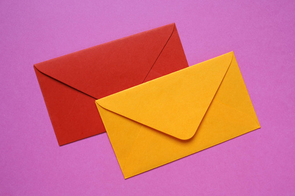 red and orange envelopes on pink background - Фото, изображение