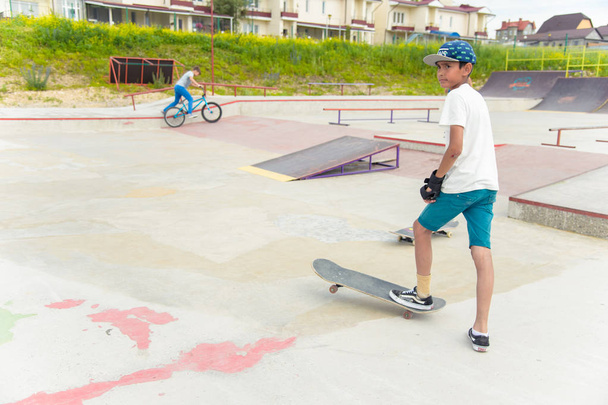 Skateboarding contest in skate park of Pyatigorsk.Young Caucasian skateboarders riding in outdoor concrete skatepark.Skaters compete for prize..Young skater boys ready to roll in on skate ramp - Foto, imagen