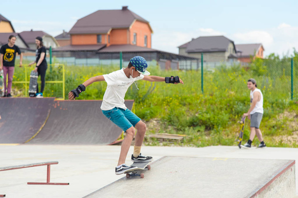 Skateboarding contest in skate park of Pyatigorsk.Young Caucasian skateboarders riding in outdoor concrete skatepark.Skaters compete for prize..Young skater boys ready to roll in on skate ramp - Zdjęcie, obraz