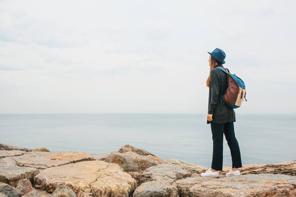 Girl traveler in a hat with a backpack next to the sea. Travel, leisure, hiking. - Fotoğraf, Görsel