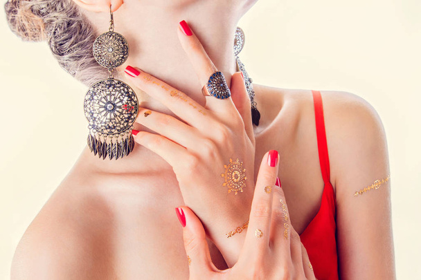 Золотий мехенді татуювання на руках жінки з червоним манікюром
 - Фото, зображення