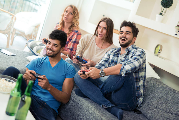 Друзья веселятся на диване с видеоиграми
. - Фото, изображение