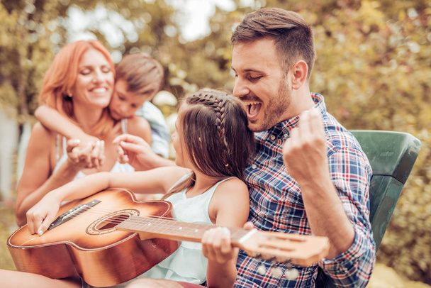 Joyeux jeune famille jouant de la guitare ensemble et riant
 - Photo, image