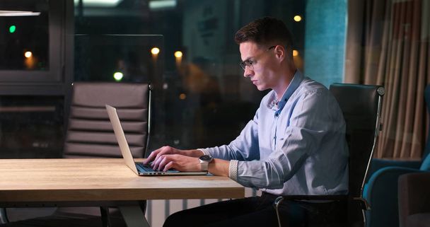 man working on laptop in dark office - Foto, Bild
