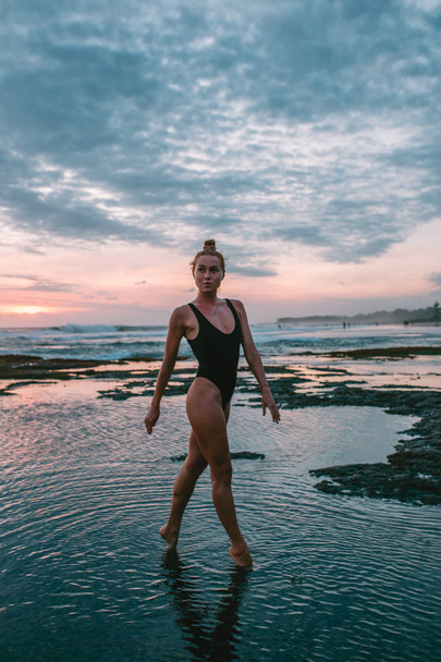 Young attractive girl practicing yoga on the beach during sunset - Photo, image
