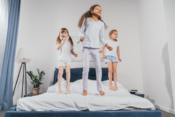 многоэтнические девочки, прыгающие на кровати
 - Фото, изображение