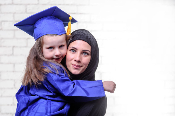 Arabe mère posant avec diplômé im école primaire fille
. - Photo, image