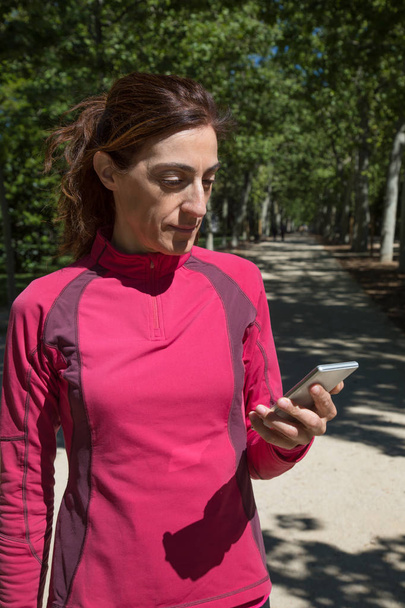 coureur femme en utilisant mobile dans parc vertical
 - Photo, image