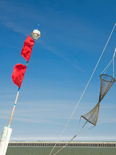 Деталі рибальського човна: буї з червоними прапорами та рибальською сіткою
 - Фото, зображення
