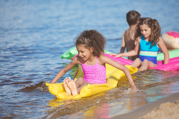 niñas multiculturales nadando en colchones inflables
 - Foto, Imagen