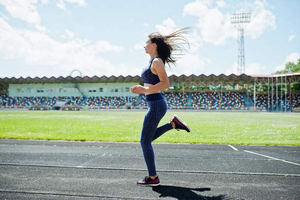 Portrait of a strong fit girl in sportswear running in the stadi - Foto, imagen
