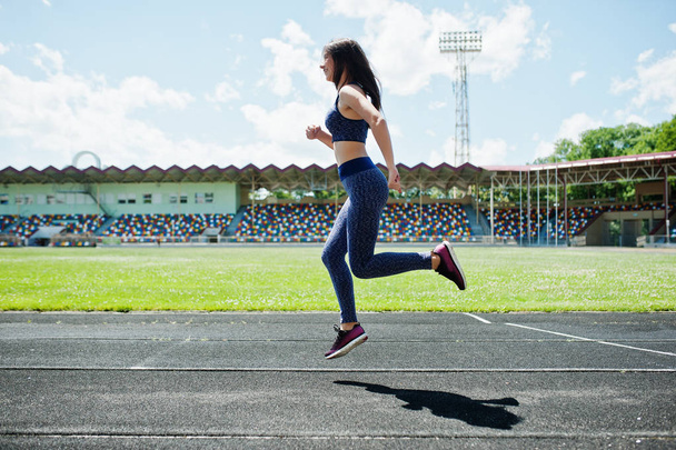 Portrait of a strong fit girl in sportswear running in the stadi - Фото, зображення