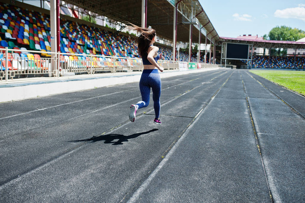 Portrait of a strong fit girl in sportswear running in the stadi - Foto, imagen