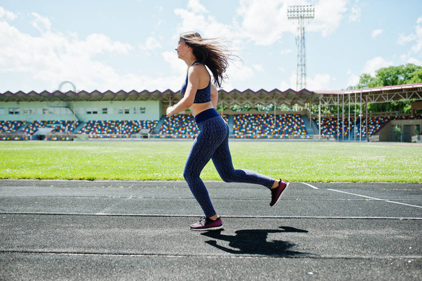 Portrait of a strong fit girl in sportswear running in the stadi - Fotografie, Obrázek