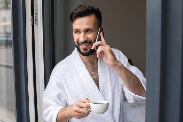 man in bathrobe talking on smartphone - Foto, Imagen