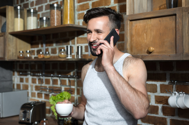 hombre con café hablando en el teléfono inteligente
  - Foto, Imagen