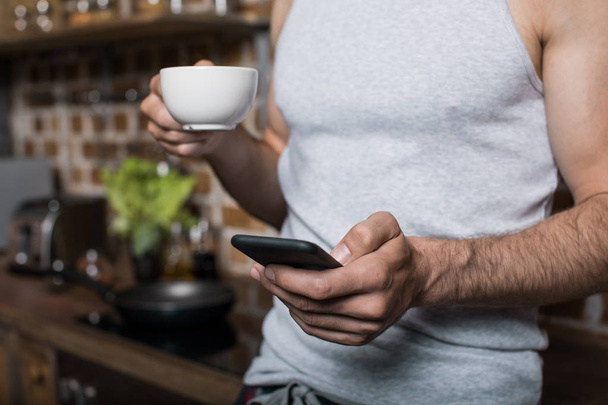 man using smartphone while drinking coffee - Foto, Imagen
