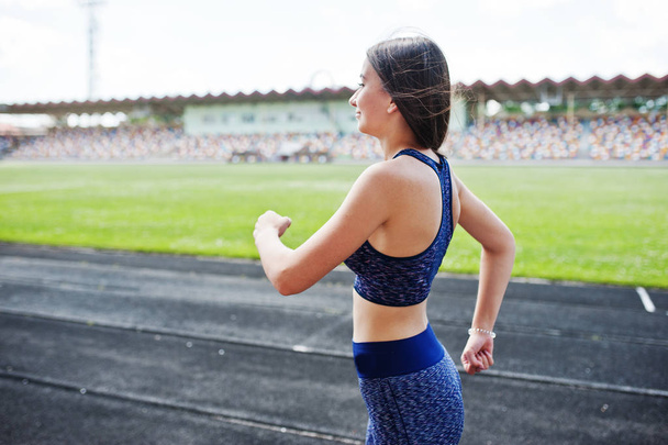 Portrait of a strong fit girl in sportswear running in the stadi - Foto, Bild