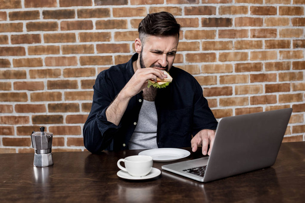 Muž přes notebook při snídani - Fotografie, Obrázek
