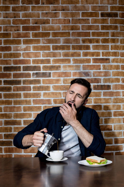 young man drinking coffee and yawning - Foto, Bild